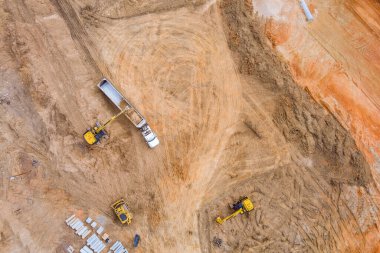 Sürüngen kazıcı iş sırasında toprağı kazar ve hava manzaralı bir çöp kamyonuna döker.