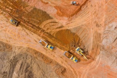 Toprağı çöp kamyonuna taşıyan bir kaç ekspres kazıcı makineli büyük inşaat alanının havadan görüntüsü.