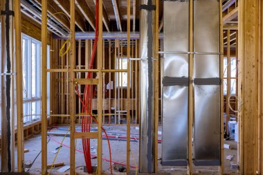 İnşaat evinin altındaki ahşap kirişlerin arasına sıcak kırmızı pex borular, havalandırma ve temizlik sistemi boruları yerleştiriliyor.