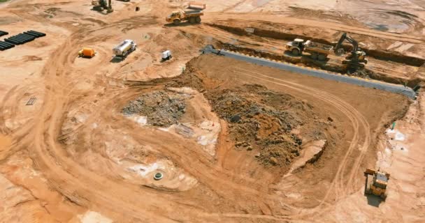 Vista aérea del sitio de construcción grande con varias máquinas excavadoras de orugas en movimiento de tierra que en el camión de volteo — Vídeo de stock
