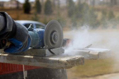 Elektrikli öğütücüyle mermer taşı keserken çıkan toz. Hızlı ve isabetli testereler için elmas bıçak.