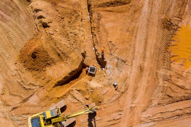 Çalışan endüstriyel makinelerle beton boru drenaj sistemi döşeyen inşaat alanının havadan üst görüntüsü