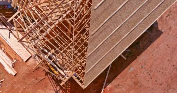 Aerial top view of construction working on the roof beams of under construction wooden built home — Stock Video
