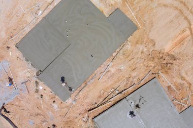 Çalışan işçiler, inşaat halindeki evdeki beton zemin ile ovalayarak çalışırlar.