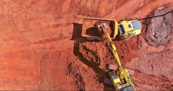 Bovenaanzicht vanuit de lucht van een graafmachine die aarde in een vuilniswagen laadt — Stockvideo