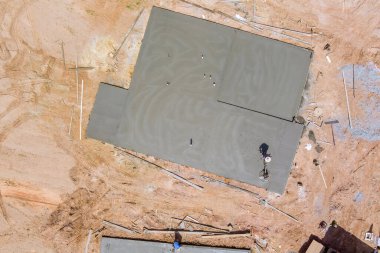 Yeni ev kompleksine çimento döşeyen makine uygulaması kullanan inşaat işçilerinin hava görüntüsü