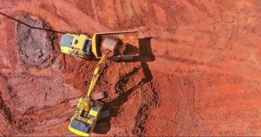 Kazı işlerinde çalışan kazıcı toprak işçilerinin inşaat sahasına beton borular döşemek için toprak kazıyor.