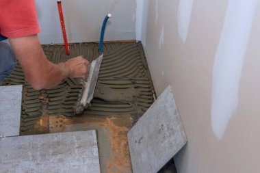 Döşeme seramik fayanslarını yerleştirme işlemi, yapışkan bazın uygulaması