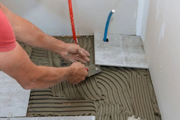 Homem colocando telha cerâmica em posição sobre adesivo — Fotografia de Stock