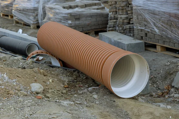 New plastics pipe awaiting installation lying on the road by repairing utilities — Stock Photo, Image