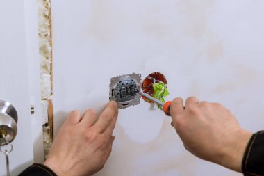 Elektrikçi yeni binanın duvarına ışıklandırma anahtarı yerleştirdi