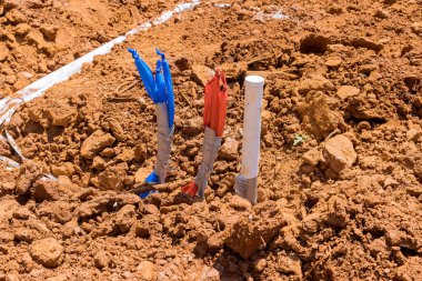 Laying water PVC plastic pipes in ground during plumbing construction site.
