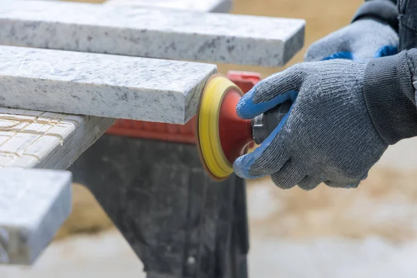 The hands of the master in with construction gloves hold a granite is polished processed — Stok fotoğraf