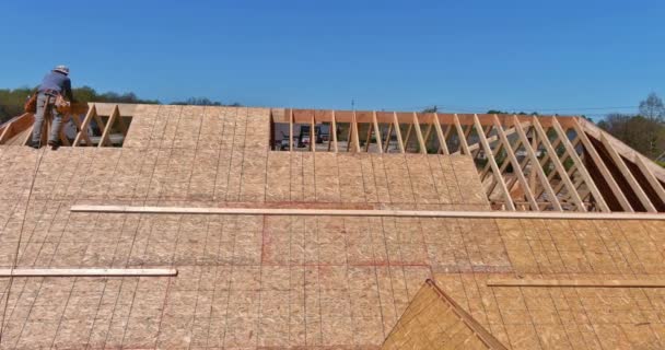 Vue aérienne du charpentier avec contreplaqué cloué sur le toit de la maison inachevée — Video