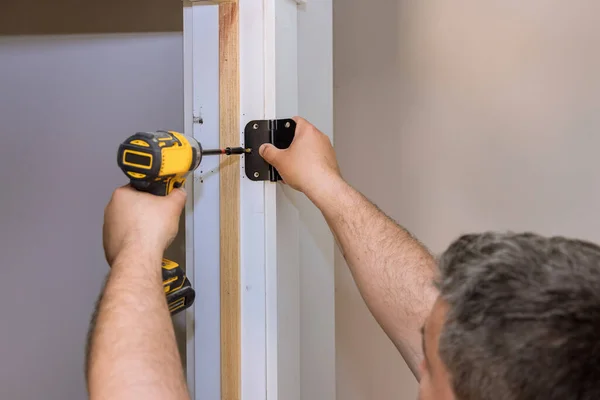 Proceso de instalación bisagras de puerta de acero inoxidable en una puerta de madera blanca — Foto de Stock