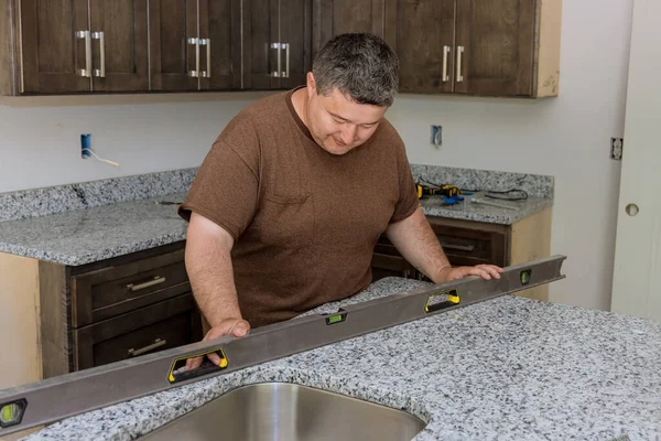 Trabajador colgando nivel de la encimera de nivelación para la nueva cocina —  Fotos de Stock