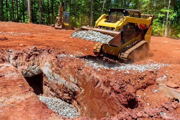 İnşaat alanında çakıl taşını taşıyan yükleyici küçük buldozerli bir inşaat alanı.