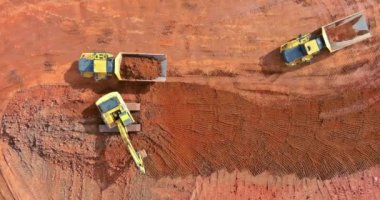 Kazı kazıcı kepçesi, konut kompleksi inşaatı için inşaat alanına hazırlanırken çöp kamyonuna toprak yüklüyor.