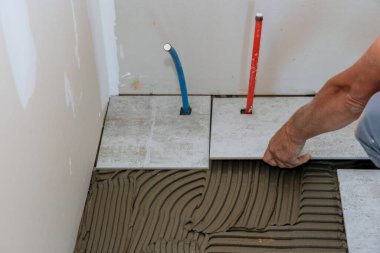 İşçinin elleri seramik fayansları yerleştiriyor.