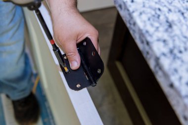 Ahşap iç kapı vida menteşesini monte eden tamircinin yakın çekimi.