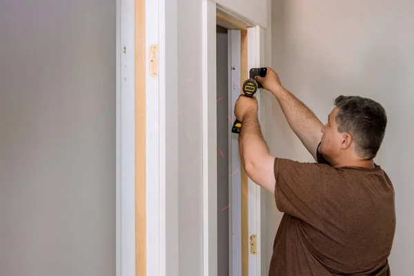 Installing the door hinge on the door frame using a screwdriver a home reconstruction — Foto de Stock