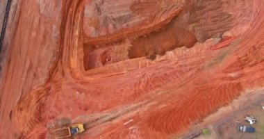 Çalışan kazıcı kepçesi, inşaat için hazırlık sahasının zeminini kazıyor.