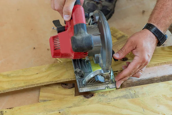 Marangoz elektrikli testereyle tahta kesiyor.