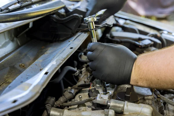 Car service with mechanic makes diagnostics and replacement on a car spark in the engine