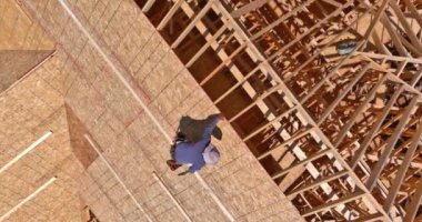 Havalı çekiç çiviyi kontrplak yüzeyden çatıya vuruyor.