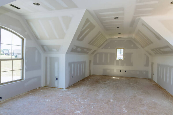 In preparation for painting an new house, finishing putty is applied to walls