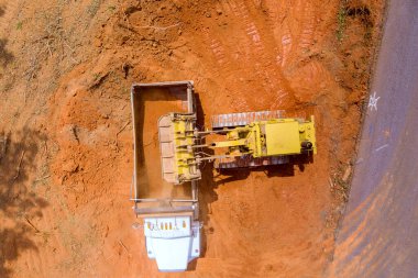 Ağır inşaat malzemelerini kullanan kazıcılar, inşaat alanına kamyon boşaltmak için toprak yüklüyorlar.