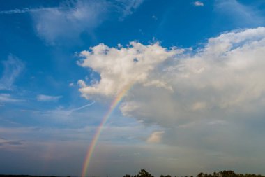 Çok renkli gökkuşağının muhteşem manzarası. Yağmurdan sonra gökyüzünde bulutlar var.