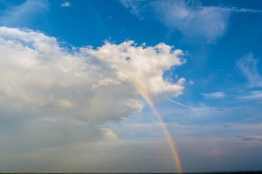 Gökyüzünde bulutlar olan yağmurdan sonra çok renkli gökkuşağının muhteşem manzarası.