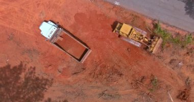 Toprağı çöp kamyonuna taşıyan bir kaç ekspres kazıcı makineli büyük inşaat alanının havadan görüntüsü.