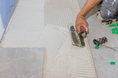 Kiremit döşemeden önce beton zemine yapıştırıcı sürmek için mala kullanan işçilerle birlikte yeniden inşa banyosu.