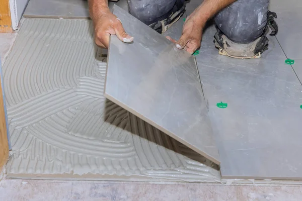 Using adhesive to install ceramic floor tiles in a home construction working project