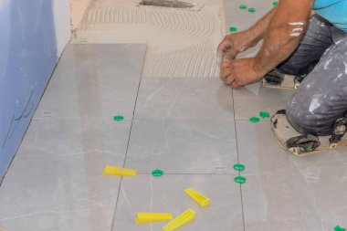 Banyodaki döşeme sistemi üzerinde çalışıyorum. Plastik raptiyelerle ve tadilatta kullanılan takozlarla.