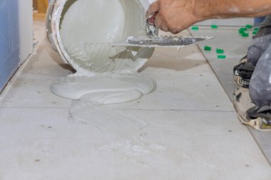 Döşeme kiremitlerini döşemek için, troweling havan mermisi beton zemine yapışır ve banyo yenileme çalışmaları yapılır.