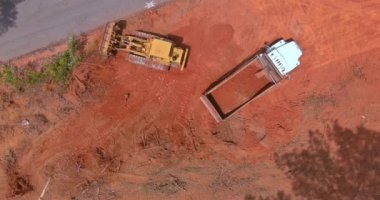 Sürüngen kazıcı çalışma süreci toprağı kazıyor ve bir inşaat alanındaki toprak hareket makinesiyle çöp kamyonuna döküyor.