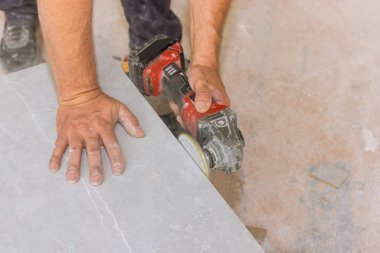 İşçi, karoların keskin köşelerini cilalamak için bir açı öğütücüden elmas cila diski kullanır.