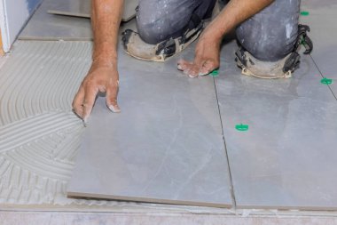 Yapışkan bir yüzeye seramik fayanslar yerleştirirken yeniden inşa banyoları üzerinde çalışıyorum.