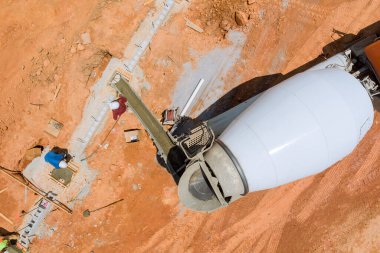 The process was pouring concrete columns to construct a new house using a concrete mixer truck.