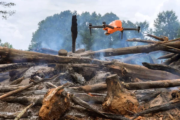 A drone is being used by the fire services to follow the fire into the forest trees in ecological disaster as result of fire.