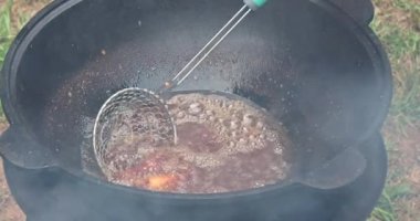 Kaynar yağda kazanda açık ateşte tavuk kanadı pişirmek.