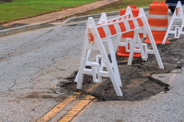 Pothole repair on damaged asphalt, with a carriageway to bypass the area where the repair is being done.