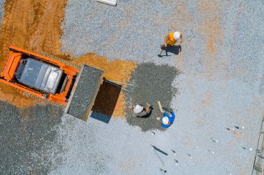 Excavator bucket working in leveling gravel the building foundation on a construction site