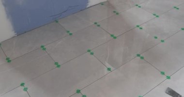 Yapıştırıcı yüzeyine seramik fayanslar yerleştiriliyor ve banyo inşaatı çalışıyor.
