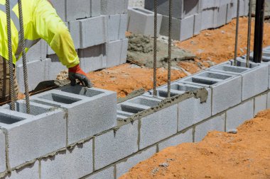 Duvarcı adam havalanan beton bloklardan bir duvar örerken duvarlara doğru yatıyordu.