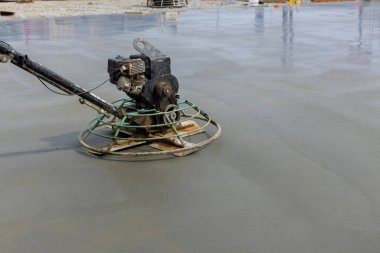 İnşaat alanındaki temel zemine dökülen çimentoyu parlatmak için işçiler tarafından beton cilalama makineleri kullanılıyor.