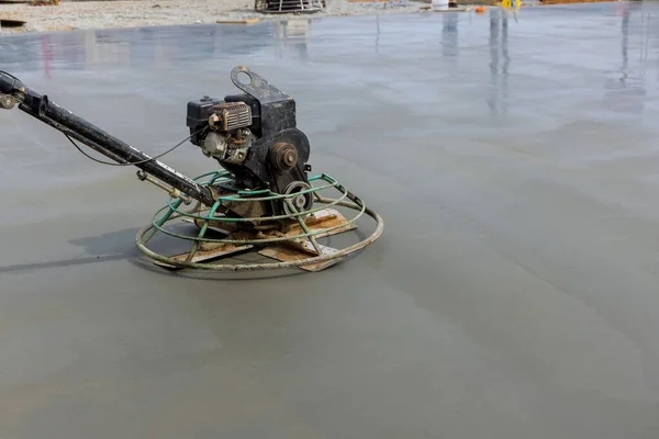 Concrete polishing machines are being used by workers to polish the cement after it has been poured on the foundation floor in construction site